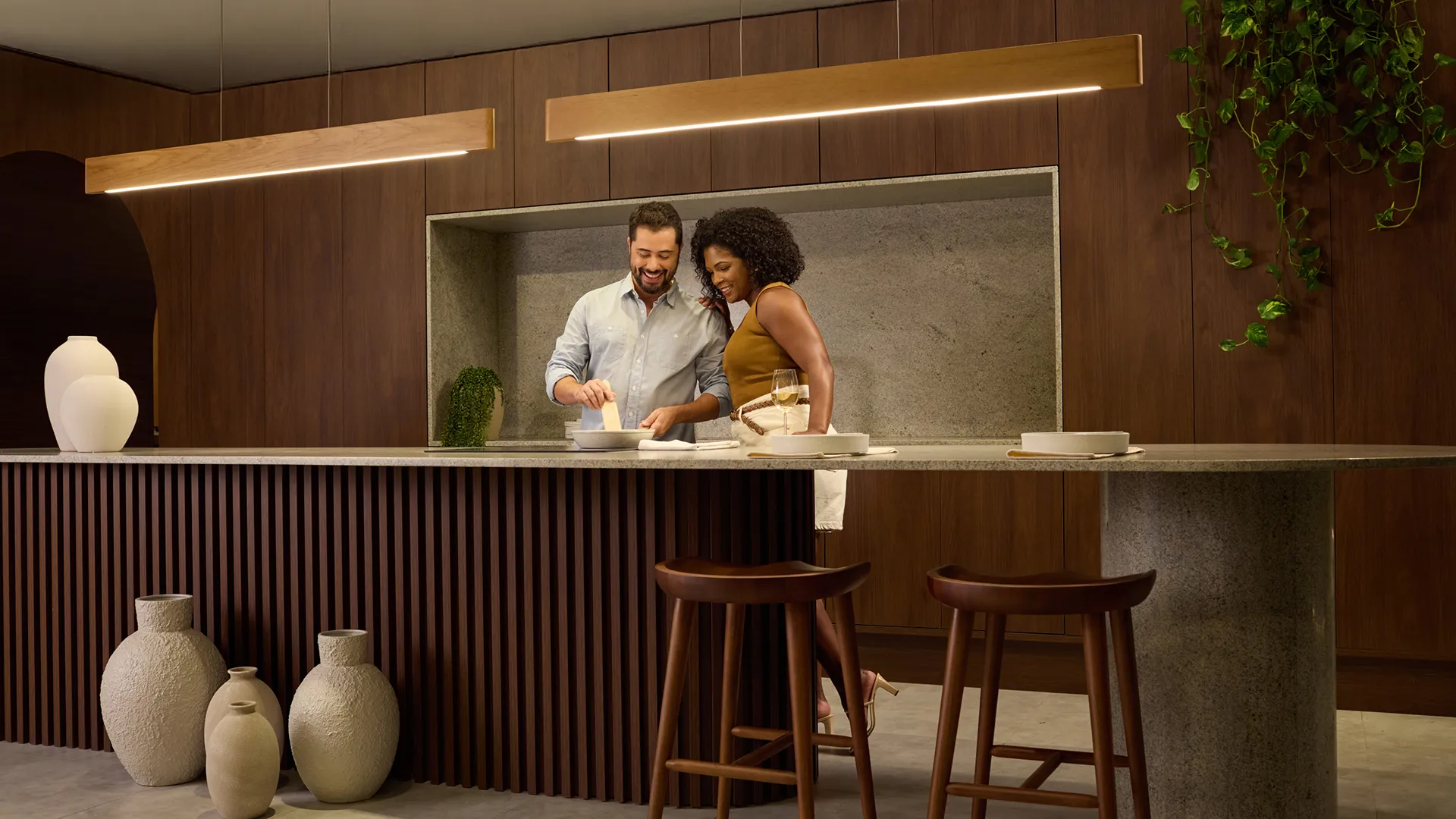 Foto de casal sorrindo em cozinha planejada moderna, tons neutros e madeira clara, luz natural suave, fotografia realista