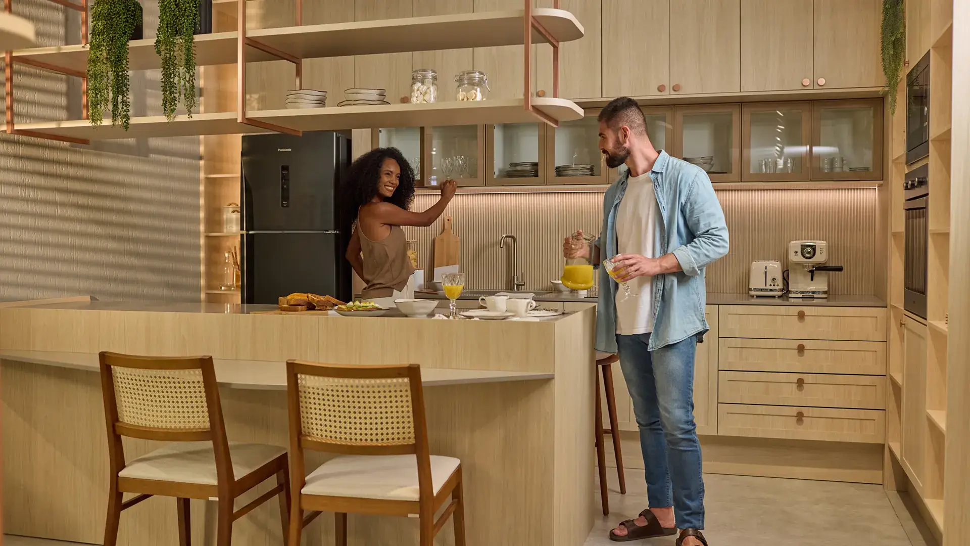 Foto de casal sorrindo em cozinha planejada moderna, ângulo lateral, tons neutros, iluminação de dia, fotografia realista